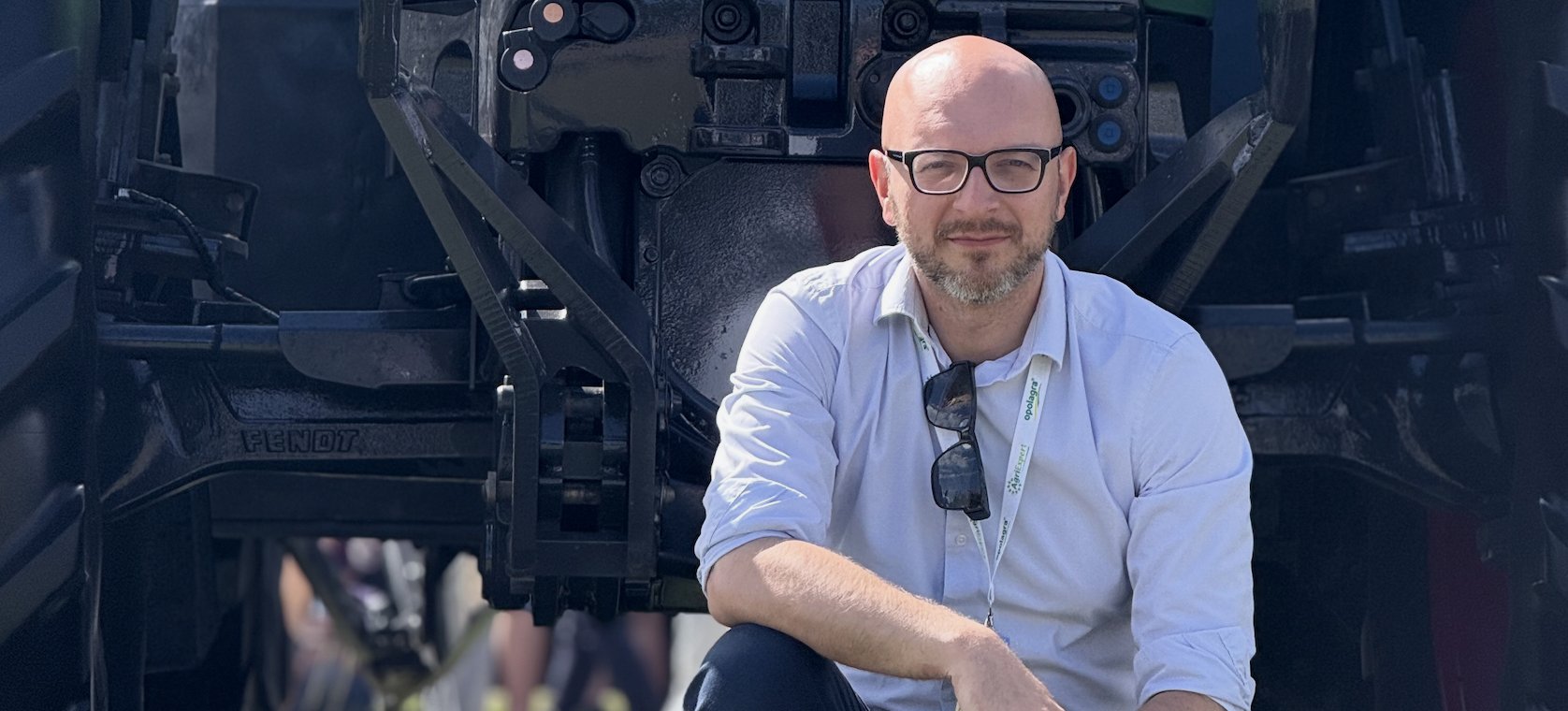 Łukasz Witkowski przed zielonym traktorem Fendt